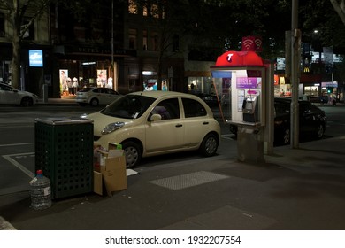 Melbourne, Australia - October 8, 2015:  Night Street Scene Of A Small Car With A Parking Fine Ticket Parked Next To A Public Payphone, In Melbourne, Australia.