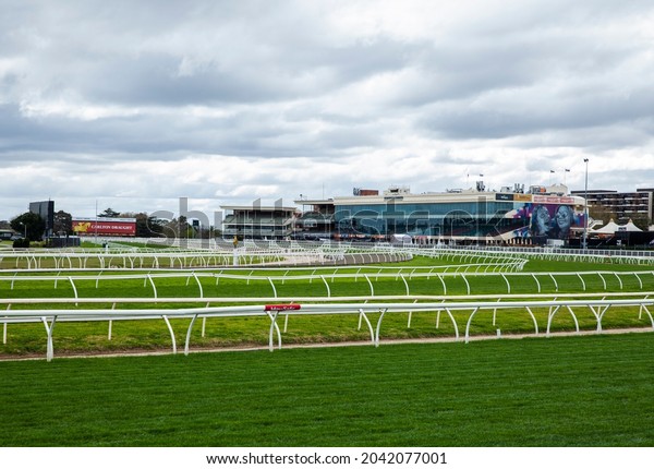 Melbourne, Victoria, Australia - 09.15.2021: The\
grandstand, barriers, billboards and lush green grass at Caulfield\
Racecourse, a famous horse racing track in Melbourne. Home of the\
Caulfield Cup.