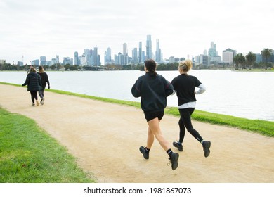 Melbourne, Victoria, Australia, 29 May 2021: Two People Running Around Albert Park Lake Against The Melbourne City Skyline Backdrop. People Out Exercising, Runners And Walkers On The Track.