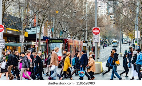 Melbourne, Victoria, Australia, July 14 2018: Five Public Transport Victoria trams are on Swanston Street while pedestrians cross the road at the intersection of Bourke Street.