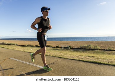 MELBOURNE, VICTORIA, AUSTRALIA - MARCH 23, 2014 - An unidentified male athlete runs along the beach during the Ironman run leg on March 23, 2014.