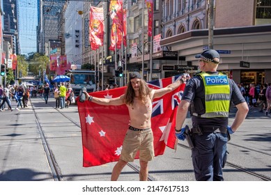 Melbourne, Victoria, Australia, March 26th, 2022: A Topless Male Protestor Is Holding An Australian Red Ensign Flag In Front Of A Police Officer During An Anti Vaccination Rally