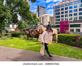 Melbourne, Victoria Australia - November 20 2021: Flagstaff Gardens Park A Woman In A Black Hat Carries Her Peaceful Protest Sign For Freedom Saying, Save Your Life Say No, In Front Of Mounted Police