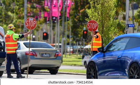 Melbourne, Victoria, Australia, October 14th 2017: Two traffic control workers holding stop signs to stop the traffic at a roundabout