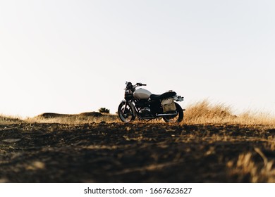 Melbourne, Victoria/Australia - 01/01/2020: Classic Motorcycle on on a hill at sunset in a country field.