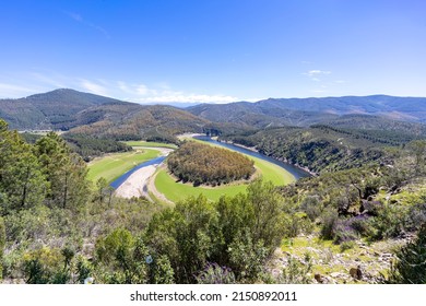 Melero Meander With Green Tones And A Blue Sky In The Province Of Cáceres During A Sunny Spring Day