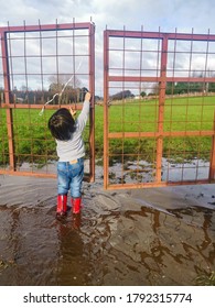 Melipeuco, Chile. August, 03, 2020: Child In A Pool Of Water Trying To Open A Gate 