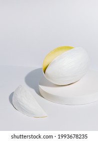 Mellon Painted In White With A Cut Slice Isolated On A White Background. Honeydew Melon Vegetable Placed On A Monochrome Matching Podium. Creative Health Food Concept.