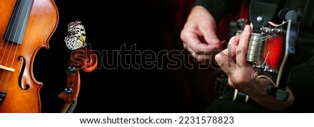 melody concept. guitarist's hands. guitarist playing the electric guitar, old violins and butterfly on black.
