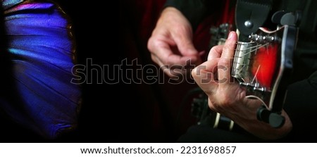 melody concept. guitarist's hands. guitarist playing the electric guitar and bright blue morpho butterfly wings on black.