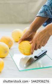 Melon berries on the kitchen table, hands cut melon into halves .