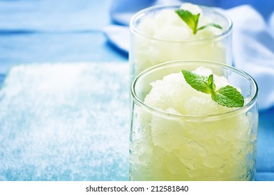 Melon Granita On Light Blue Background. Tinting. Selective Focus On Mint