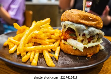 Melted Cheese Oozing Down A Hot Hamburger With Seasoned French Fries