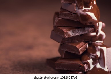melted chocolate pouring into a piece of chocolate bars with green mint leaf on a table