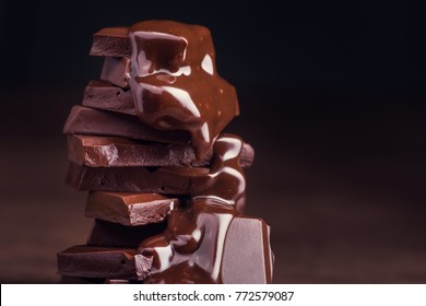 geschmolzene Schokolade, die zu einem Stück Schokoladenriegel mit grünem Minzblatt auf einem Tisch gießt