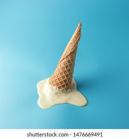 Melted ice cream with ice cream cone on pastel blue background. Minimal summer food concept.