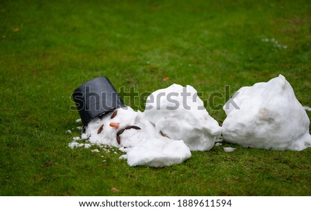 A melted snow man with a sad face as symbol of the end of the winter.
