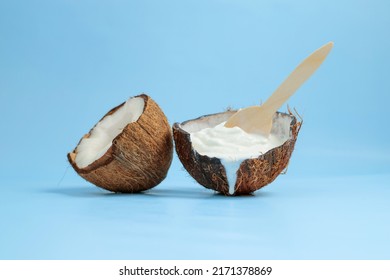 Melted soft coconut ice cream, two coconut halves on a blue background. Coconut pleasure. Coco milk. Coco taste