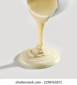 melted white chocolate pouring on white background - Shutterstock ID 2198761871