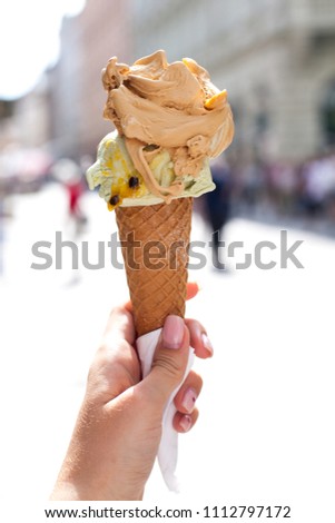 melting delicious ice cream in waffle cone gelato pistachio salty caramel holding female hand