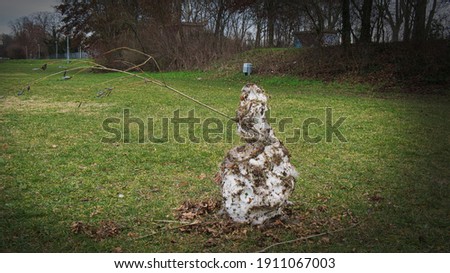 A melting, dirty snowman with a branch is symptomatic of mild winter and the no longer perceptible cold in times of climate change and global warming