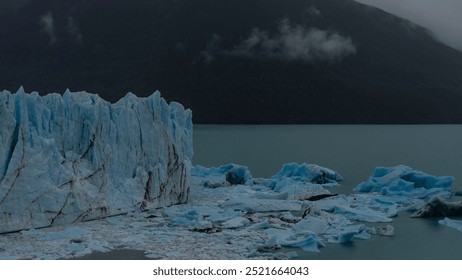 A melting glacier. A wall of cracked blue ice rises above a glacial lake. Melted ice floes float in turquoise water. The coastal mountains are in a fog. Cloudy. Perito Moreno. El Calafate. Argentina.  - Powered by Shutterstock