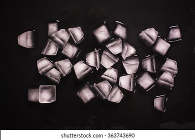 Melting ice cubes over black stone background. Top view. Selective focus