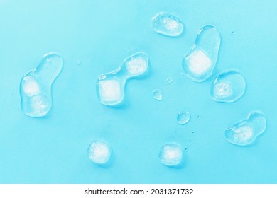 Melting ice cubes scattered on a blue background, top view. Texture.