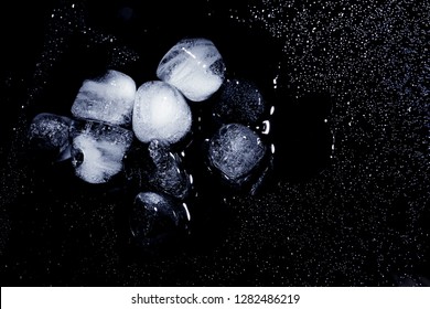 Melting Ice Cubes And Water Drops On Black Background, Top View. Space For Text