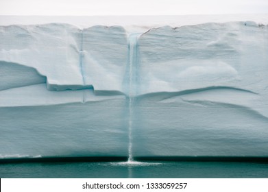 Melting ice forms waterfall falling into sea over edge of glacier wall due to global warming in Northern Arctic. Climate crisis and breakdown - Image