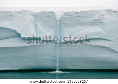 Melting ice forms waterfall falling into sea over edge of glacier wall due to global warming in Northern Arctic. Climate crisis and breakdown - Image