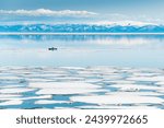 Melting ice on Baikal lake. Kayak sailing between ice floes on the lake. Baikal, Siberia, Russia. Beautiful spring landscape.