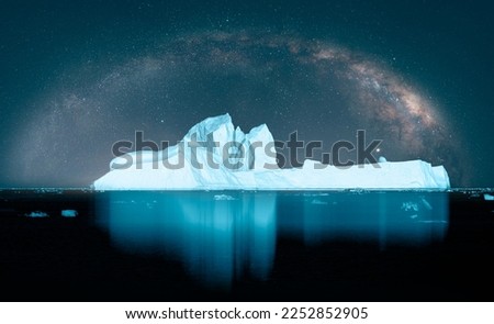Melting icebergs by the coast of Greenland with milky way galaxy -  Melting of a iceberg and pouring water into the sea - Greenland