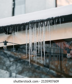 Melting Icicles Are Hanging From The Roof. Concept Of Risk And Damage Because Of The Melting Snow And Ice Outdoor