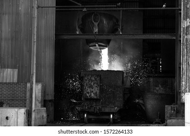 The Melting Metal Is Pouring Into The Melting Pot Of The Carriage In The Industrial Foundry Plant. The Manufacture Of Cast Metal Relies On Furnace Technologies, Since Metals Usually Melt At Very High.