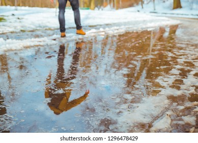 melting snow. big puddle. man trying to pass through. spring is coming
