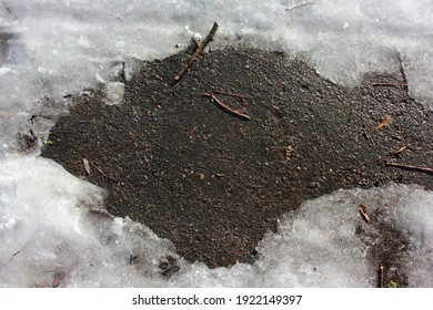 Melting Snow On The Asphalt Street During Spring Thaw. Patch Of Sidewalk In Thawing Snow. Sunny Day. Selective Focus