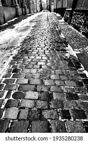 Melting Snow On The Road With Granite Paving Stones In Poznan, Monochrome