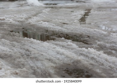 Melting Wet Snow On The Roads In The City In Spring. Wet Rut In The Snow On The Sidewalk.