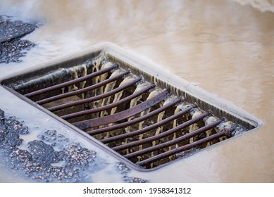 Meltwater Runs Like A Stream Into The Storm Drain Grate