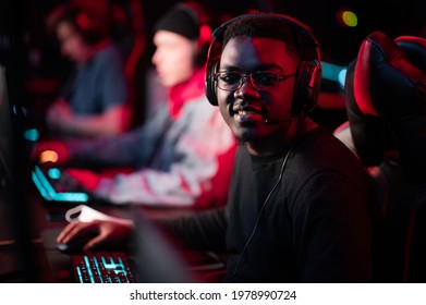 A Member Of The Esports Team At A Bootcamp Training Session. Portrait Of A Black Guy With Glasses At A Gaming Computer With A Glowing Keyboard.