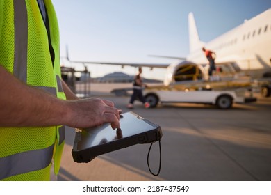 Member of ground crew preparing airplane before flight. Worker using tablet against plane at airport. - Shutterstock ID 2187437549