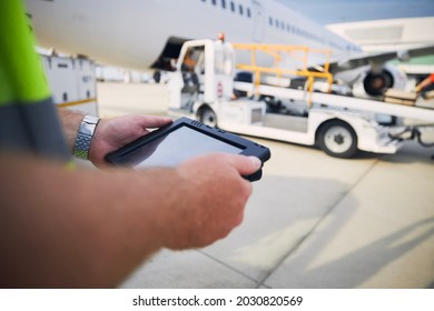 Member Of Ground Staff Preparing Passenger Airplane Before Flight. Worker Using Tablet Against Plane At Airport.