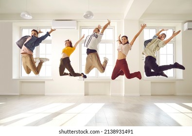 Members of a contemporary choreography dance crew jumping high up in the air all together. Group of happy, cheerful, excited, agile, energetic young people having fun in a bright hall room interior - Powered by Shutterstock