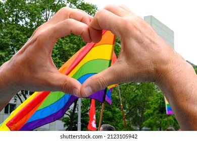 Members Of LGBTq Movement, Gay Pride Parade In City With Rainbow Flags, Demonstration Of People, Mass March Of Lesbian, Gay, Bisexual, Minority Festival, Male Hands Close Up Gesture Heart