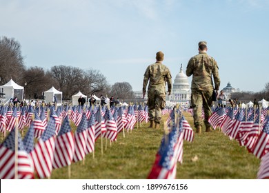 Members of the United States Air Force walk through and collect flags at the Field of Flags the day after the inauguration on January 21, 2021, in Washington D.C.