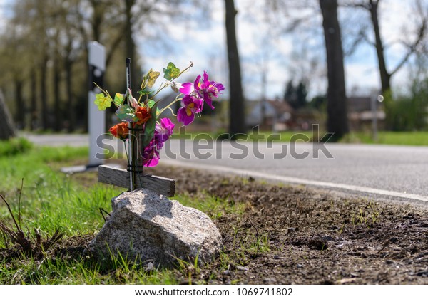 Memorial cross with flowers at the scene of an\
accident at the\
roadside