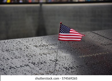 Memorial at Ground Zero Manhattan for September 11 Terrorist Attack with an American Flag Standing near the Names of Victims Engraved - Shutterstock ID 574569265