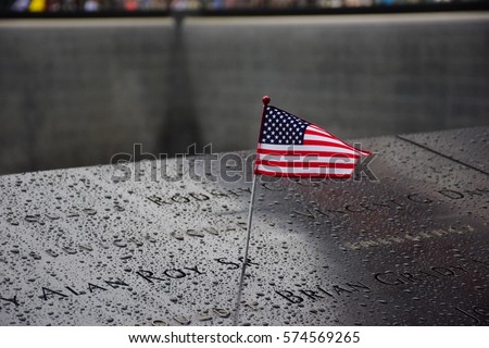 Memorial at Ground Zero Manhattan for September 11 Terrorist Attack with an American Flag Standing near the Names of Victims Engraved