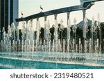 Memorial and rows of fountains illuminated by sunlight at sunset or sunrise in the Independence Square at summertime, Tashkent, Uzbekistan.